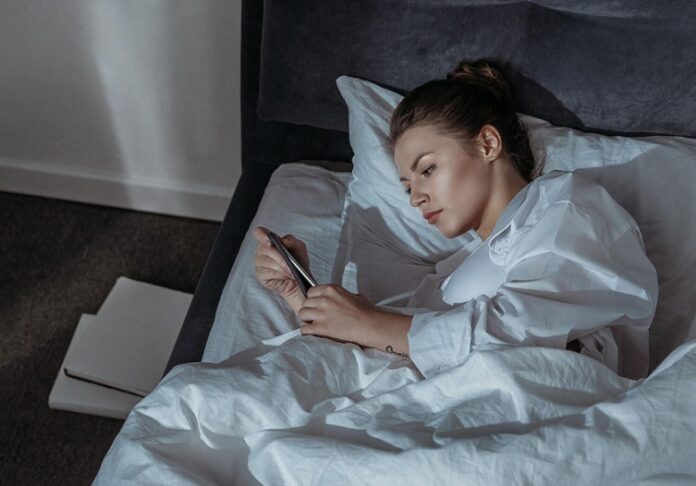 Девушка со смартфоном в кровати